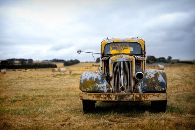 A yellow old car in the field. A yellow old car in the field.